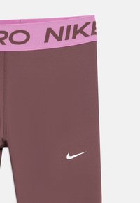 Bordeaux Nike trening tights med rosa livsermer som har "NIKE PRO" tekst og hvit Nike swoosh-logo på venstre lår.