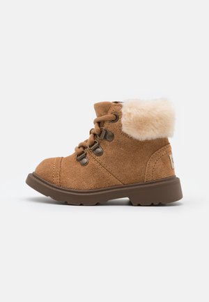 Bottine en daim marron avec doublure en fourrure, lacets à l’avant, œillets métalliques et semelle en caoutchouc épaisse, conçue pour les temps froids.