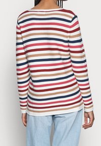 Haut à manches longues avec des rayures horizontales rouges, bleues, beiges et blanches. Texture côtelée avec un col rond et une coupe décontractée.