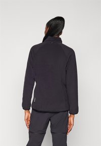 Black fleece jacket featuring a high collar and raglan sleeves. Smooth texture, zippered side pocket, and a rounded hem.