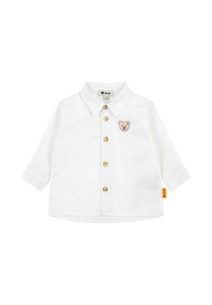 Weißes Babyoberteil mit langen Ärmeln und Kragen, fünf Knöpfen vorne und kleinem Teddybär-Aufnäher auf der linken Brust.