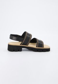 Černé kožené sandály se dvěma širokými pásky, k nimž se hodí kontrastní žluté prošívání. Robustní béžová podrážka s texturovaným černým základem.
