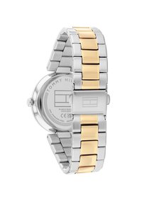 Reloj de acero inoxidable con una pulsera de metal en tonos plateado y dorado. Caja redonda y un cierre seguro; parte posterior marcada con la marca y detalles de resistencia al agua.