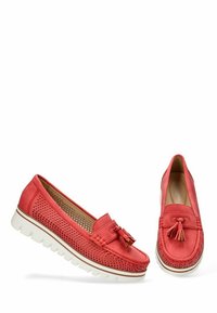 Mocasines de cuero perforado en color coral con un acento de borlas, suela de goma blanca y detalles de franjas en contraste. Presentan una punta redonda y un diseño sin cordones.
