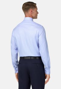 Lichtblauw geruit overhemd met lange mouwen, knoopsluiting en effen manchetten. Draag het met donkerblauwe pantalons en een zwarte riem.