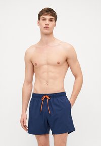 Námorné plavky so širokým elastickým pásom a oranžovým šnúrkou. Majú bočné vrecká a hladký, ľahký materiál.
