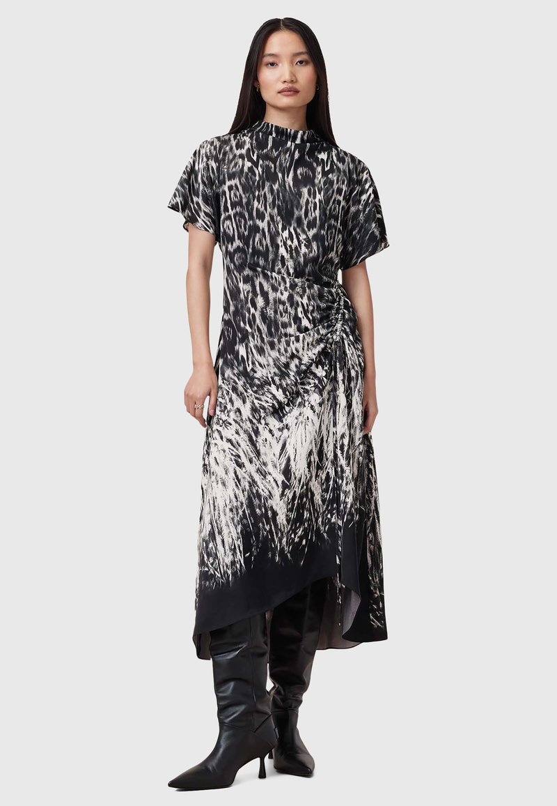 Vestido de leopardo en blanco y negro con mangas cortas, dobladillo asimétrico, detalle fruncido en la cintura y textura de tela suave.
