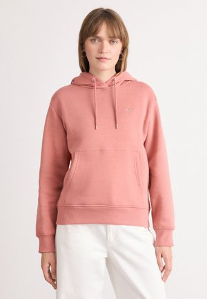 Rosa hettegenser med lomme i front og ribbede mansjetter. Sølv snor og en liten logodetalj nær brystet.