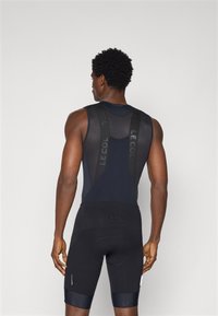 Schwarze Radsport-Bib-Shorts mit Netzträgern, figurbetontem Design und Polsterung. Ausgestattet mit markierten Akzenten in einer kontrastierenden Textur. Rückansicht dargestellt.