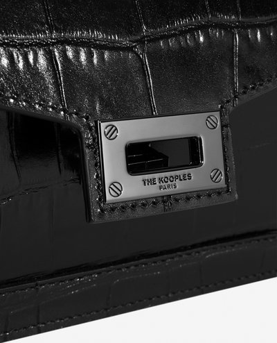 Borsa nera in pelle sintetica di coccodrillo, caratterizzata da una forma rettangolare, una texture lucida e una chiusura metallica con il nome del marchio impresso.
