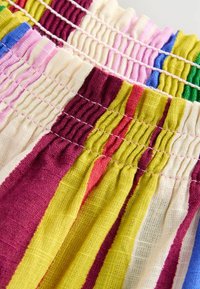 Elastic waistband fabric shorts with bright horizontal stripes in yellow, pink, green, and purple, featuring a textured linen-like material.