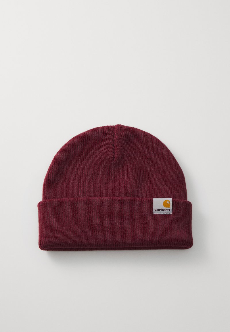 Burgundy knit beanie hat with a folded cuff and a square leather logo patch featuring a yellow emblem and text on the front.