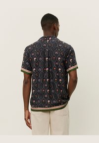 Short-sleeve shirt in dark fabric featuring a floral pattern in pink and orange, with a green and striped hem and collar detailing.