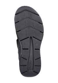 Semelle de chaussure en caoutchouc noir avec un motif texturé, comportant des rainures et des crans pour l'adhérence. Comprend le nom de la marque en relief près du talon.