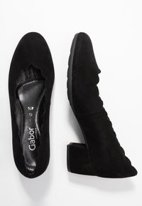 Bottines en daim noir à talons avec un design à bords festonnés. Elles possèdent une semelle intérieure rembourrée et un talon carré épais pour plus de stabilité.
