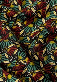 Baumwollstoff mit schwarzem Hintergrund zeigt ein sich wiederholendes Blumenmuster in Rot, Grün, Gelb und Weiß, das Textur und Farbkontrast betont.