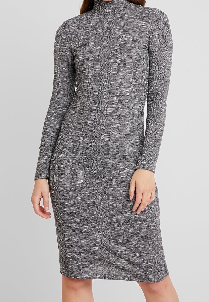 Harmaa pitkähihainen mekko, jossa on korkea kaulus, teksturoitu kuvio ja vartalonmyötäinen leikkaus, ulottuen polviin.