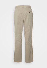 Beżowe bawełniane spodnie o prostym kroju nogawek. Posiadają tylną kieszeń z guzikiem. Brak widocznych wzorów i dodatkowych elementów metalowych.