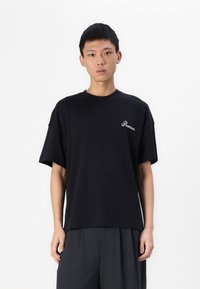 Tricou negru cu mânecă scurtă, fabricat din material neted, având un mic logo alb "Premium" pe partea stângă a pieptului. Design cu croială dreaptă.