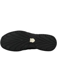 Sole di scarpa sportiva nera con superficie in gomma testurizzata, caratterizzata da un motivo a zigzag e un emblema centrale con logo.