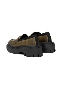 Masívne nazúvacie topánky s tmavooranžovým koženým zvrškom, ktoré majú širokú čiernu gumovú podrážku a textúrovaný detail na päte.