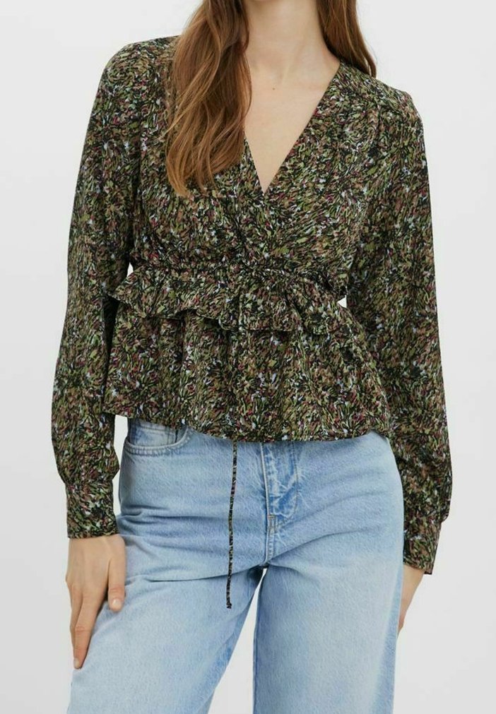 Zelená halenka s květinovým potiskem, dlouhými rukávy, zavinovacím střihem a řaseným lemem. Kombinováno s světle modrými džíny s vysokým pasem.