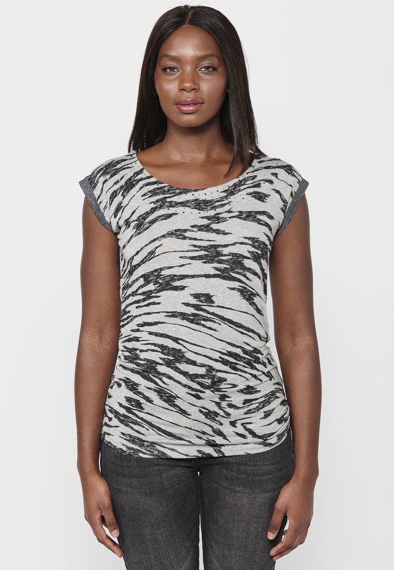 T-shirt rayé gris avec un motif zebra noir, décolleté rond et manches courtes en forme de cap. Associé à un jean foncé, au design ajusté.