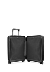 Valise rigide noire avec une poignée de transport, quatre roues et une ouverture zippée révélant un intérieur en mailles et deux compartiments.