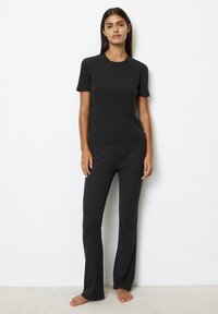 Camiseta negra de cuello redondo y pantalones a juego, hechos de una tela suave y elástica. Ambos artículos tienen un diseño ajustado, con un mínimo detalle de costuras.