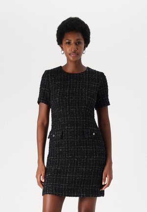 Black tweed dress with a fitted silhouette, short sleeves, and two front pockets adorned with silver buttons. Textured fabric with a grid pattern.