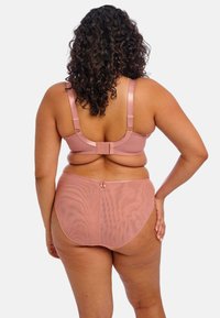Ensemble de lingerie rose comprenant un soutien-gorge avec des bretelles réglables et une fermeture à crochets, associé à des culottes taille haute assorties en material transparent.