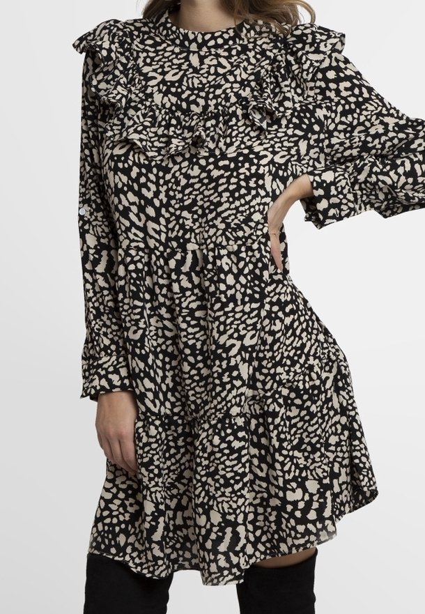 Vestido negro y beige con estampado, cuello con volantes y mangas largas, que presenta una falda de capas y una textura de tela ligera.