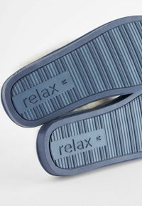 Zilā gumijas čības ar ribotām zolēm, ar izteiktu "relax" logotipu. Mīksta tekstila oderes redzama gar malām.