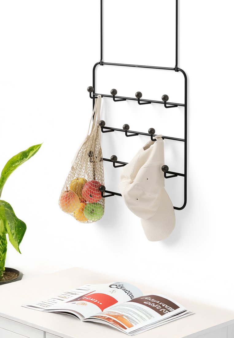 Rack da parete in metallo nero con sei ganci; presenta un cappuccio bianco e una borsa di rete che contiene mele colorate appese.