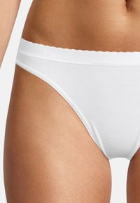 Weiße Baumwollstringtanga mit gewelltem Bund und tonalem Logo-Detail. Glatte Textur mit einer figurnahen Passform.
