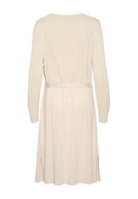 Abito lavorato a maglia beige con maniche lunghe, scollo rotondo e spacchi laterali. Include una cintura coordinata in vita per una vestibilità regolabile.