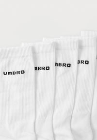 Calzini bianchi alla caviglia con texture a costine e logo "UMBRO" nero stampato sui lati. Confezione da cinque, design uniforme.