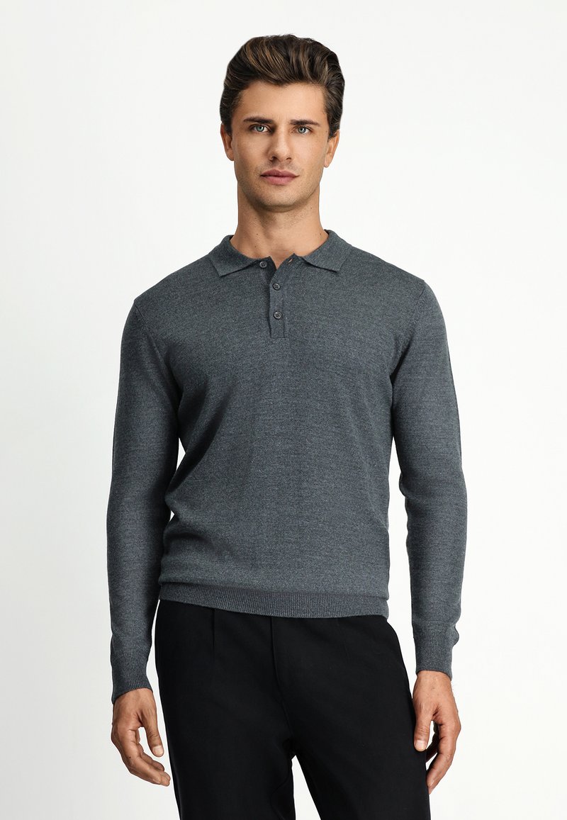 Szara longsleeve polo wykonana z miękkiego materiału, z kołnierzykiem i trzema guzikami, w zestawieniu z czarnymi spodniami.