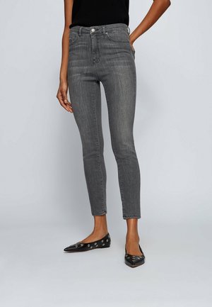 Gray denim skinny jeans with a high waist, front pockets, and a fitted design. Paired with black flats featuring metallic accents.