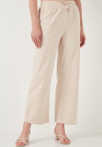 Beige wide-leg trousers made of lightweight fabric, featuring a drawstring waist. Smooth texture with subtle stitching details.