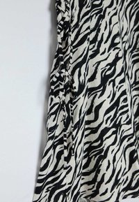 Tessuto a righe zebra bianco e nero appeso con legature sui lati, caratterizzato da una superficie texture e da una forma fluida e fluttuante.