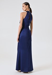 Navy satin Abendkleid mit hohem Kragen und Schlüsselloch-Design im Rücken. Hat eine figurbetonte Silhouette und kleine Knöpfe am Rücken. Glatte Textur.