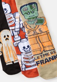 Tri par halloween-themed nogavic: črne z duhom, oranžne s okostnjakom in svetlosmeđe z obliko Frankensteina ter besedilom.