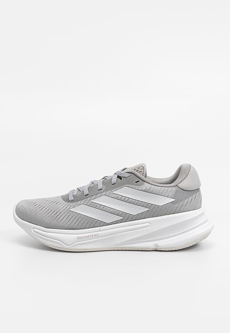 Grauer Adidas Laufschuh mit weißem Drei-Streifen-Logo, gepolstertem Schuhsohle mit der Bezeichnung "Dreamstride" und gestricktem Obermaterial, Seitenansicht auf weißem Hintergrund.
