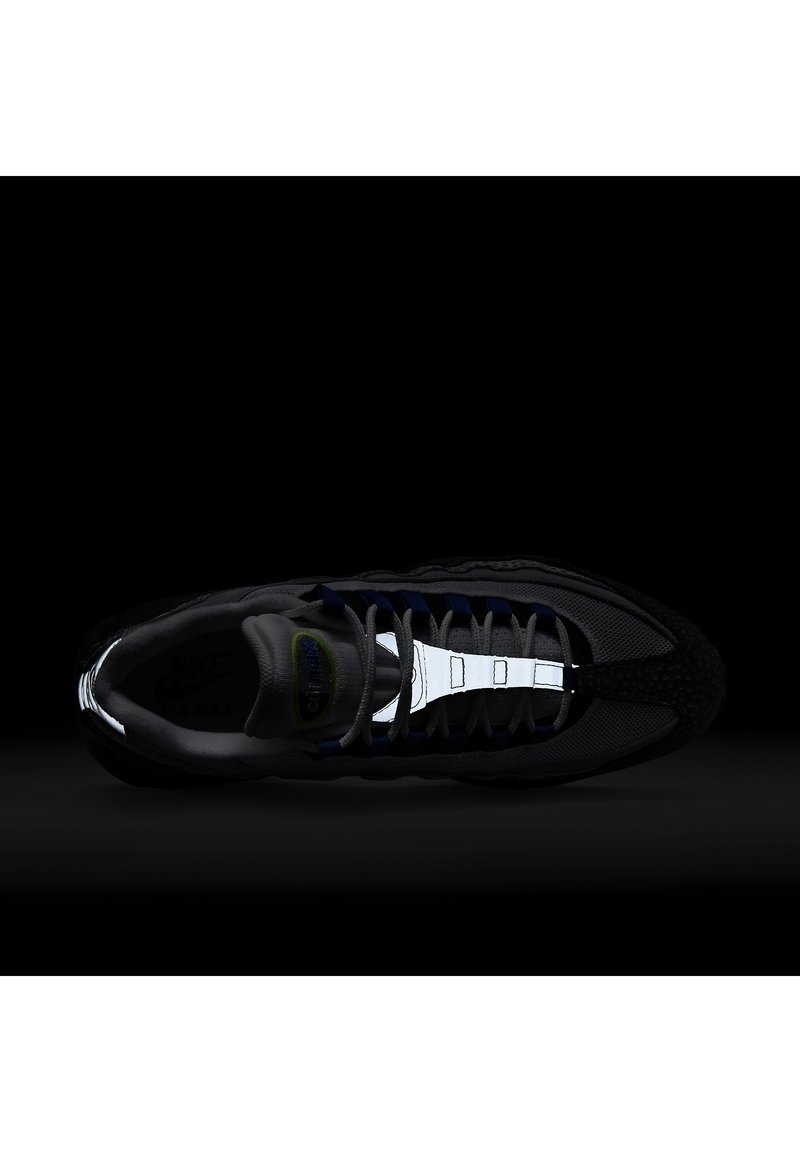 Zapatilla Nike Air Max en negro con acentos en gris y azul. Presenta una parte superior de malla, suela texturizada y detalles reflectantes en los cordones.