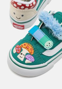 Grønn stoff-sneaker med et fargerikt brodert soppdesign, hvite detaljer og en blå borrelåsstripe med luftig kant.