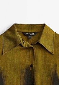Chemise à col vert olive avec des boutons noirs et l'étiquette Massimo Dutti indiquant la taille EUR 38, USA 8 et MEX 28.