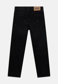 Vaqueros de mezclilla negra con diseño de pierna recta. Incluyen bolsillos traseros y una etiqueta de cuero marrón claro con la marca en la cintura.