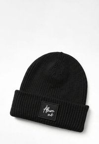 Black beanie made of ribbed knit material, featuring a folded cuff and a rectangular label with white text on a black background.