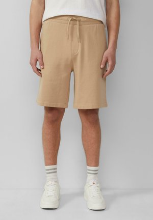 Shorts en coton beige avec une taille élastique, un cordon de serrage, des poches latérales et une coupe droite. Ourlet plat sans motif ni accents.
